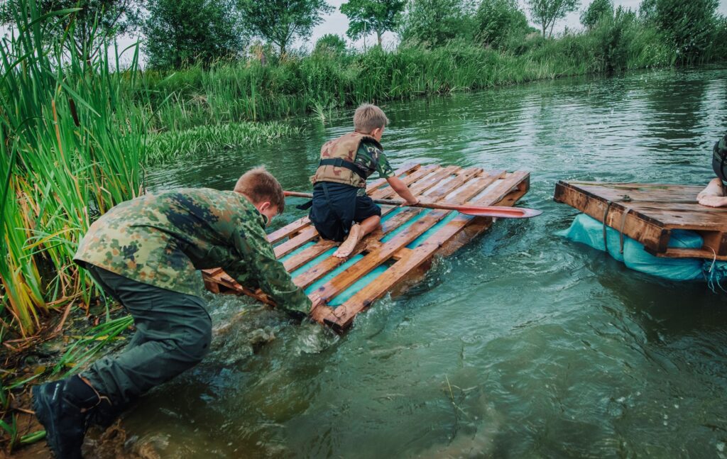 Uśmiechnięci uczestnicy nad jeziorem, obóz rekreacyjny NatureCamp gwarantujący dobra zabawa i pełny relaks po intensywnym dniu.